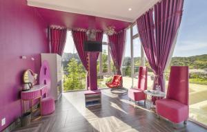a living room with pink furniture and large windows at Mac Valley DaLat Hotel in Da Lat