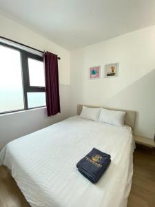 a bedroom with a white bed with a blue bag on it at Da nang seaview MT apartment in Danang