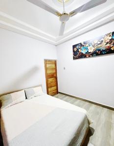 a white bedroom with a bed and a ceiling fan at Fofana Luxury Suites in Sotuom