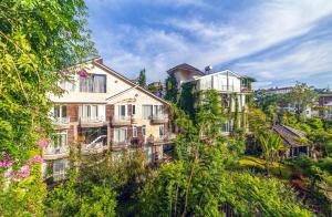 a large building on the side of a hill with trees at Mac Valley DaLat Hotel in Da Lat