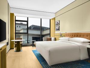 a bedroom with a large white bed and a television at Four Points by Sheraton Shanwei Lufeng in Shanwei