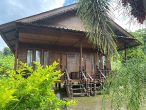 a small wooden house with a porch and a palm tree at ปายเรือนไทย in Pai
