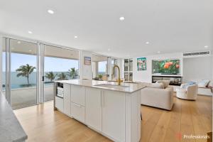 a kitchen and living room with a view of the ocean at Waters Edge On Wattle, Absolute Beachfront Luxury in Yeppoon