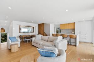 a living room with a couch and a kitchen at Waters Edge On Wattle, Absolute Beachfront Luxury in Yeppoon