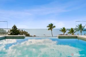 a swimming pool with a view of the ocean at Waters Edge On Wattle, Absolute Beachfront Luxury in Yeppoon