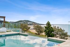 a swimming pool with a view of the beach at Waters Edge On Wattle, Absolute Beachfront Luxury in Yeppoon