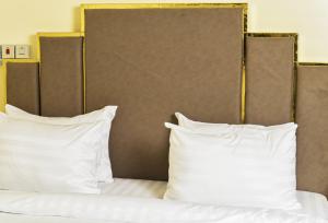 a bed with white pillows and a brown headboard at Tunjor Homes in Barikin Jirga Summa