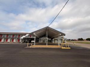 a building with a large roof in a parking lot at Thunderbird Motel Hillsboro in Hillsboro