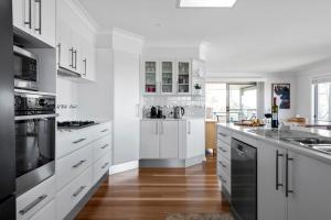 a white kitchen with white cabinets and black appliances at Foredeck Views in Manyana