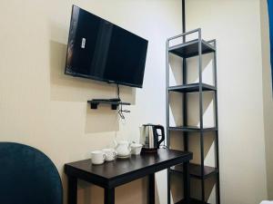 a table with cups and a television on a wall at Backpackers Tashkent in Tashkent