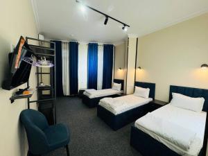 a hotel room with two beds and a chair at Backpackers Tashkent in Tashkent