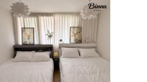 two beds in a bedroom with white sheets and pillows at binna stay 이태원역7분, 독채,테라스,4 Queen Beds, 무료짐보관 , 명동,홍대,서울역,명동 15분 in Seoul
