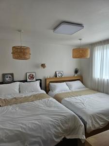 two beds in a bedroom with white sheets at binna stay 이태원역7분, 독채,테라스,4 Queen Beds, 무료짐보관 , 명동,홍대,서울역,명동 15분 in Seoul