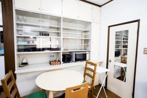 a kitchen with white cabinets and a table and chairs at Mikansei Stay in Higashi-murayama