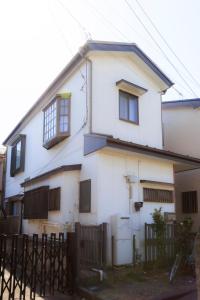 a white house with a fence in front of it at Mikansei Stay in Higashi-murayama
