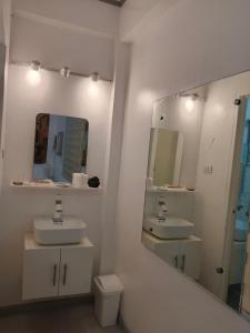 a white bathroom with two sinks and a mirror at Villa Adela Pension House in Balamban