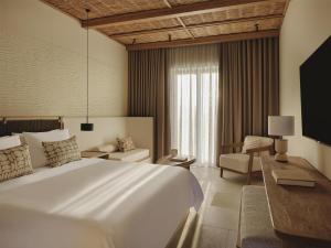 a hotel room with a large white bed and a chair at Parian Chronicle Hotel Paros, Destination by Hyatt in Kampos Paros +56 photos