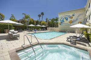 a swimming pool with chairs and umbrellas at a hotel at Redondo Beach Hotel, Tapestry Collection by Hilton in Redondo Beach