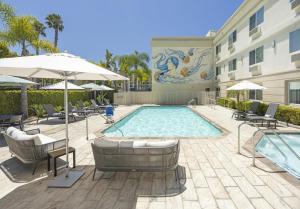 a pool with chairs and umbrellas next to a building at Redondo Beach Hotel, Tapestry Collection by Hilton in Redondo Beach