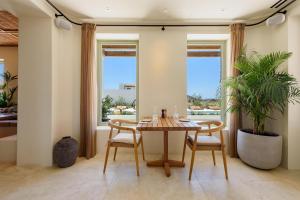 a dining room with a table and chairs and windows at Parian Chronicle Hotel Paros, Destination by Hyatt in Kampos Paros