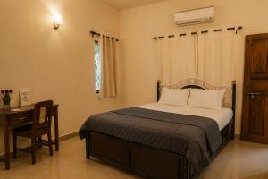 a bedroom with a bed and a desk and a window at Goan Villa Anjuna Beach in Anjuna