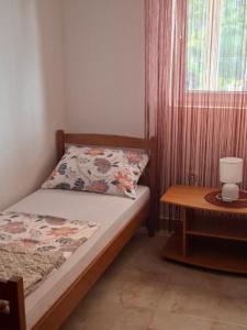 a small bedroom with a bed and a table at Sandra Apartmani 1 in Zaostrog