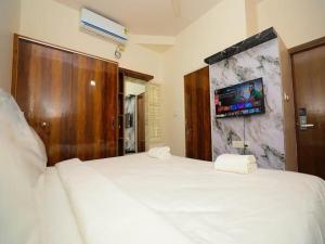 a bedroom with a white bed and a tv on the wall at AMV Airport Residency in Bangalore