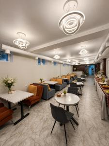 a restaurant with tables and couches and chairs at Dosman Hotel Bishkek in Bishkek