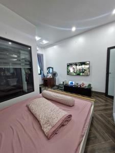 a bedroom with a pink bed and a flat screen tv at Home Phong Vân in Hâu Thon