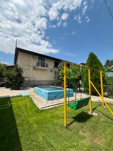 a swing in a yard with a house at Dosman Hotel Bishkek in Bishkek