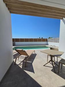an outdoor patio with tables and a swimming pool at Divina Loft C Modern Loft with Shared Pool in Perivolia