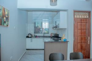 a kitchen with white cabinets and a counter with chairs at Obama Apartments in Mbweni