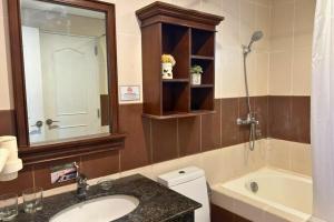 a bathroom with a sink and a tub and a mirror at Crosswinds Swiss Deluxe Suite in Tagaytay