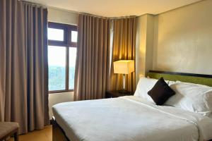 a hotel room with a bed and a window at Crosswinds Swiss Deluxe Suite in Tagaytay