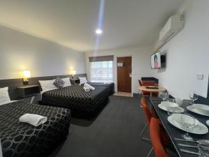 a hotel room with two beds and a table at The Cottage Motor Inn Albury CBD in Albury