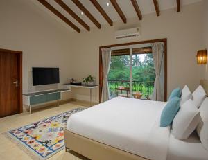 a bedroom with a large bed and a television at Lamrin Morjim Goa in Morjim