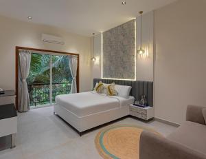 a bedroom with a white bed and a window at Lamrin Morjim Goa in Morjim