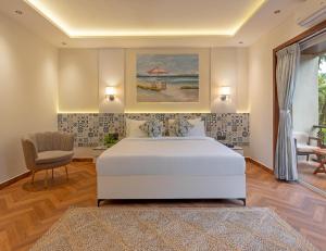 a bedroom with a white bed and a chair at Lamrin Morjim Goa in Morjim +50 photos