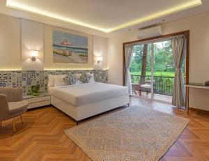 a bedroom with a white bed and a balcony at Lamrin Morjim Goa in Morjim