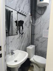 a bathroom with a white sink and a toilet at Саратан отель in Osh