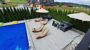 a patio with chairs and an umbrella and a pool at Apartamenty Borysek De Lux in Białka Tatrzańska