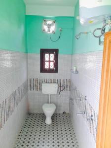 a bathroom with a toilet and a window at sicsac inn in Jorhat