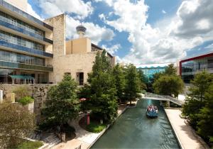 a boat on a river in front of a building at Grand Hyatt San Antonio River Walk in San Antonio
