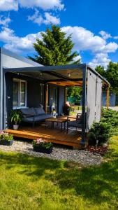 a house with a deck with a couch and a table at Tiny House Valea Avrigului in Avrig