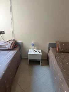 ein Zimmer mit zwei Betten und einem Tisch mit einer Flasche darauf in der Unterkunft lot24 in Saidia 