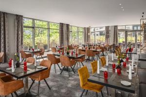 a restaurant with tables and chairs and windows at Ramada by Wyndham Essen in Essen