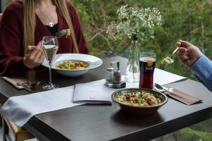 Eine Frau sitzt mit einer Schüssel Essen an einem Tisch. in der Unterkunft Hotel Ostredok in Demänovská Dolina