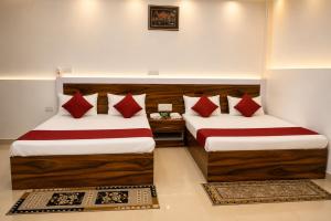 two beds in a room with red pillows at Hotel Jayaditya Palace in Ayodhya