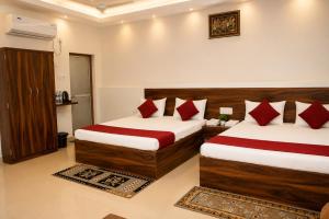 a hotel room with two beds with red pillows at Hotel Jayaditya Palace in Ayodhya
