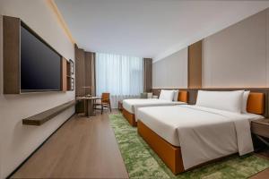 two beds in a hotel room with a flat screen tv at Wyndham Garden Datong Ancient City in Datong
